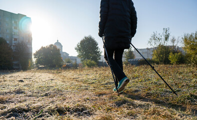 A woman is engaged in Nordic walking near the stadion. Woman stretching in the park listening to...