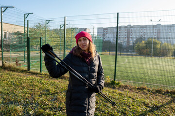 A woman is engaged in Nordic walking near the stadion. Woman stretching in the park listening to...