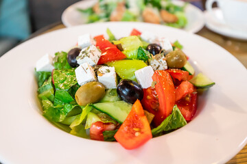 Greek salad with feta cheese and olives on a plate in a cafe as a symbol of Mediterranean cuisine and diet