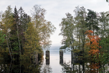 An old stone gate way connecting two mirror blank lakes together on an autumn or fall day