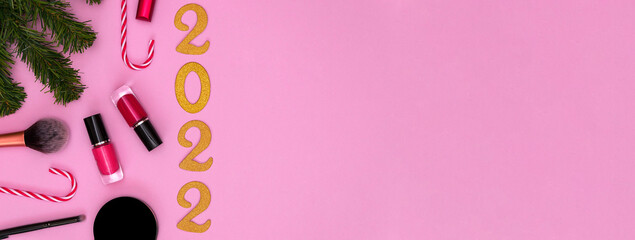 Happy New Year 2022. Golden numbers, fir branches and cosmetics on a pink background. the concept...