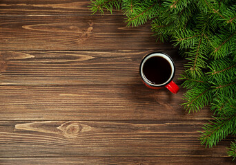 Fototapeta na wymiar Christmas background fir branches with a red cup of coffee on a wooden background.