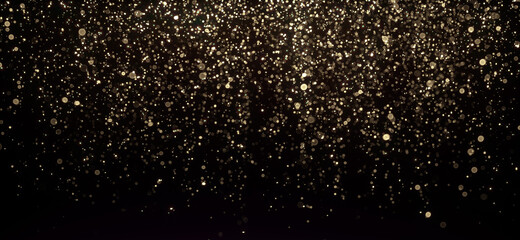 Gold glitter texture on black. Shinny small particles reflecting light.