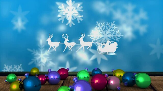 Animation of santa claus in sleigh with reindeer over snow falling and christmas baubles, on blue
