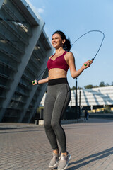 Health and sport practice. Young motivated athletic woman in sport wear doing jumping rope...