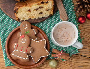 Traditional christmas gingerbread cookies and panettone over a wooden table