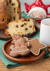 Traditional christmas gingerbread cookies and panettone over a wooden table