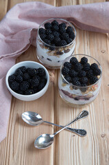 Top view of glasses with blackberry cheesecake on a wooden background. Healthy snack