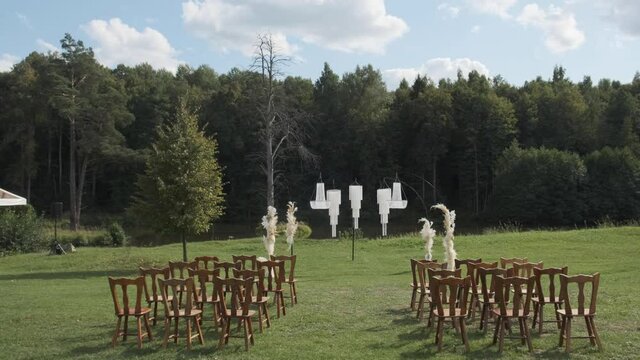 outdoor chandelier decor with green grass and forest backdrop for wedding reception