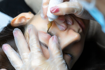tattoo artist performs permanent makeup of eyelashes