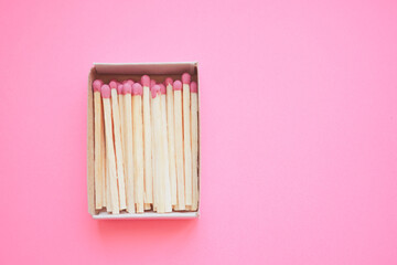 Matches in an open box on a pale pink paper table.