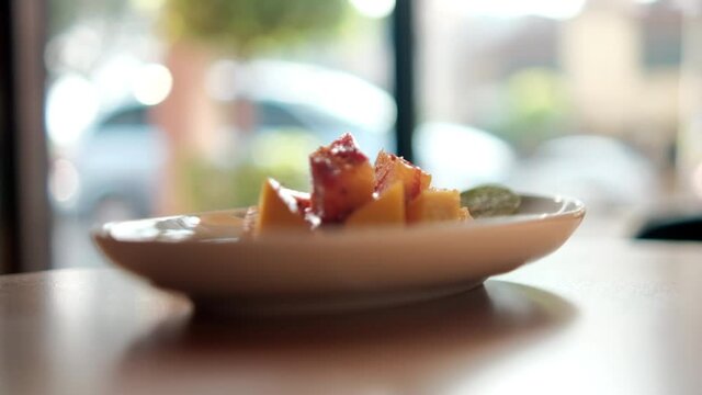 Plate of chopped mango with Mexican chamoy sauce and blurry background