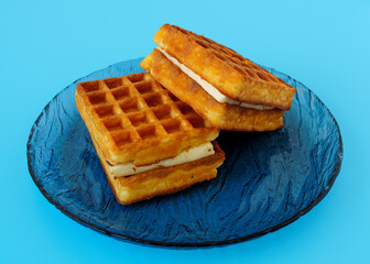 Delicious soft waffle dessert with ice cream souffle on blue background