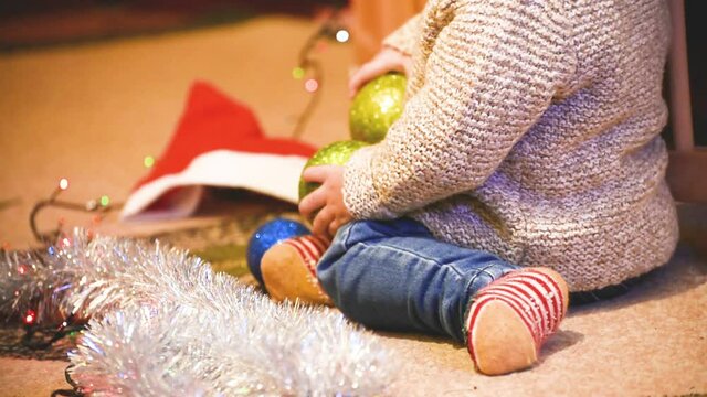 Close-up infant boy playing with Christmas balls, night before Christmas. kid's arms holding balls , lesure time during holidays