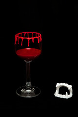 Bloody decorated wineglass as a scary halloween drink on black background, decorated with fangs and space for copy text.