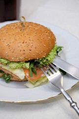 Juicy burger in a plate with cutlery