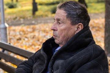 A lonely senior man sitting on the bench in park