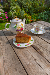Tea and cake for one on a wooden table outside in the garden