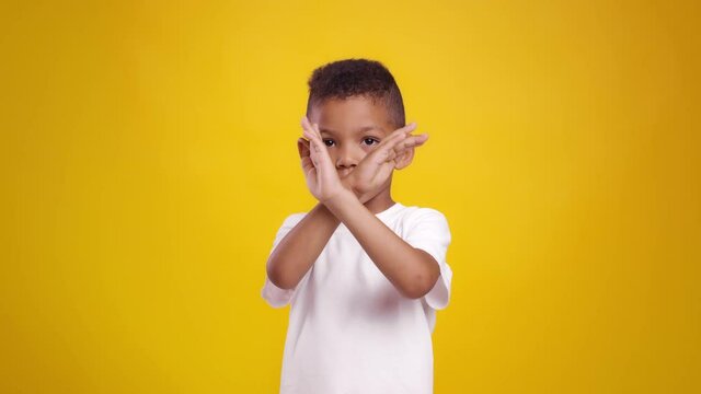Stop kids abuse. Cute little african american boy crossing hands, showing rejection gesture to camera