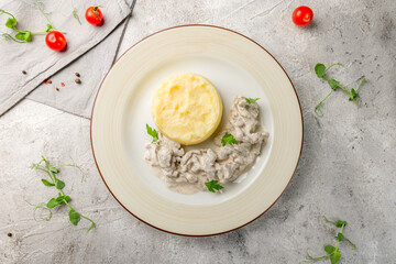 Stroganoff from beef with mashed potatoes on plate top view on grey table