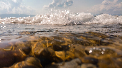 Waves on a stone beach, the texture of the transparent clear waters of the lake