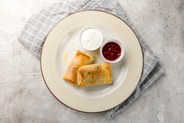 pancakes with sour cream and raspberry jam on plate top view on grey table