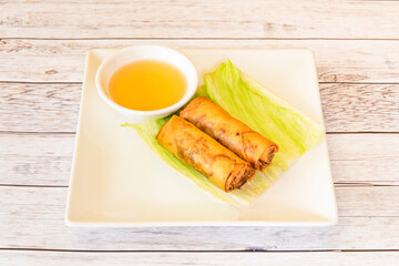 Crispy rolls stuffed with fried fish with sauce for dipping on white plate