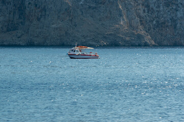 White boat sailing close to the coast blue aegean sea in Greece