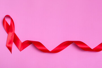 Top view on pink background with red ribbon concept December 1st International AIDS Day close-up.