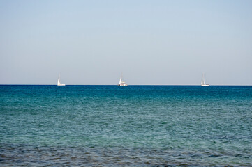 3 White boats sailing in the open blue aegean sea in Greece