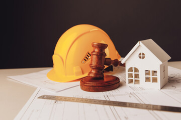 Gavel and construction plans with yellow helmet and house