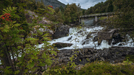 Fototapeta na wymiar Waterfall and river in Norway. Old dam and bridge over the river.