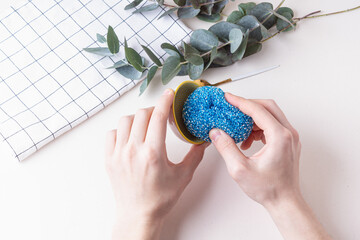 Man washes a plate with sponge. Blue steel wool sponge. Natural and eco-friendly things for the...