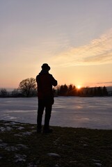 man photographs the sunset in a snowy landscape
