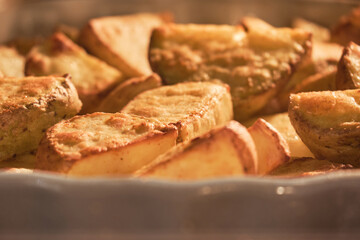 Sliced potatoes are baked on a platter in a home kitchen oven, close-up