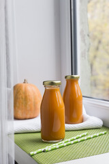 Pumpkin juice in a bottle light background, two bottles, pumpkin on the windowsill