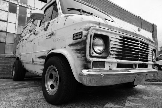 Creepy old cargo van with rust and worn paint in black and white