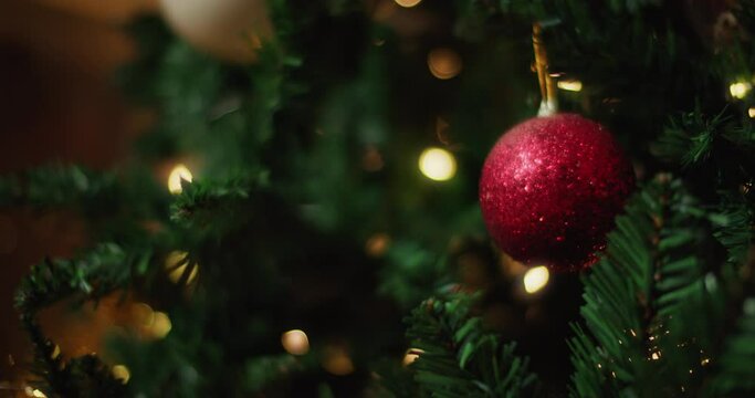 Close up of a red glittering ball hanging on a Christmas tree. Slow motion. 