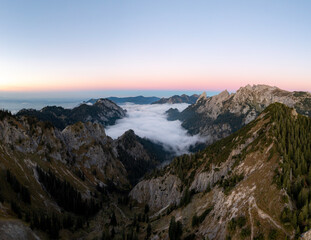 Naklejka na ściany i meble Sonnenuntergang in den Ammergauer Alpen bei Hochnebel