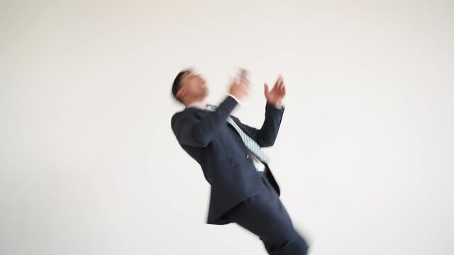 Businessman in a blue jacket and tie texting on the phone stumbles and falls. Man in business clothes walks and falls comically on his back. Funny bad luck situation on a white background.