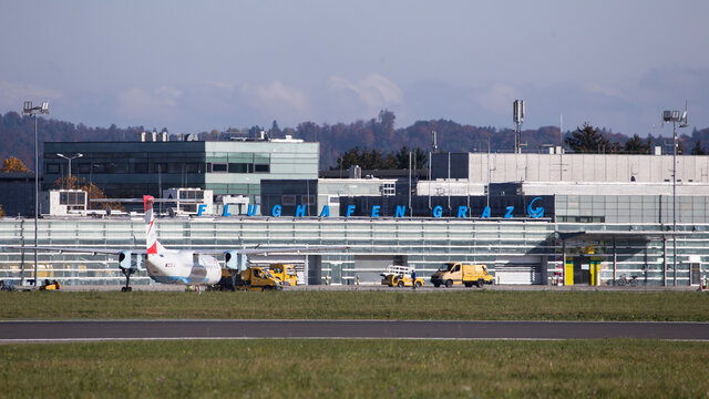 Austrian regional aircraft parked in front of terminal at airport Graz and waiting for passengers
