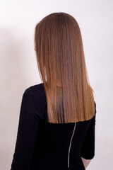 
Female back with long straight healthy brunette hair in hairdressing salon