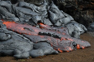 Pahoehoe lava flow at Fagradalsfjall, Iceland. Lava crust is gray and black, molten lava is red and orange. New lava lobe forming.