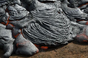 Pahoehoe lava flow at Fagradalsfjall, Iceland. Lava crust is gray and black, molten lava is red and orange. New ropy lava lobe forming.