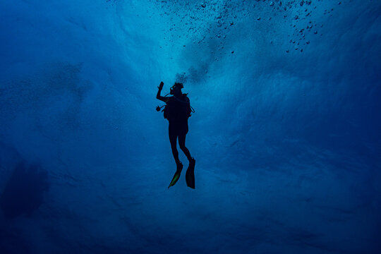Woman scuba diver swimming in deep blue