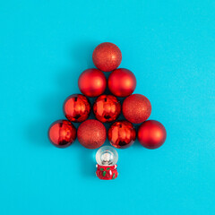 Christmas tree made of red decorations and little Santa Claus. Creative minimal composition. Sky blue background. 2022