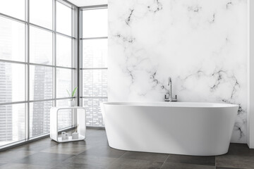 Fototapeta na wymiar Bright bathroom interior with white bathtub, tile concrete floor
