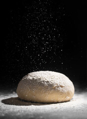 Yeast-free dough with pouring flour on a dark background