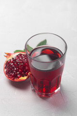 Jug of pomegranate juice with pieces of pomegranate fruits on a white background