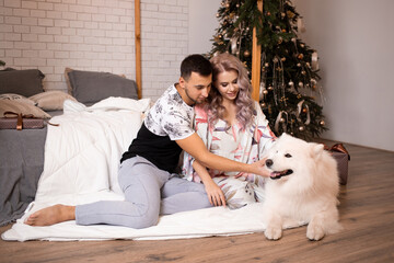 Young couple hugging in Christmas time with samoyed dog